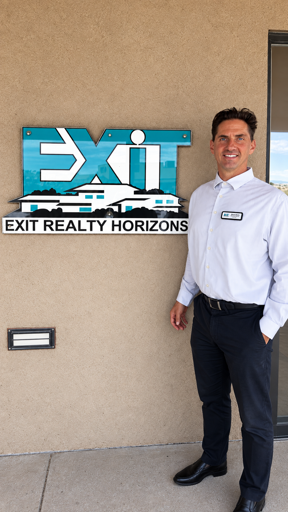 Brett Stein standing next to the EXIT Realty Horizons office sign in Las Cruces
